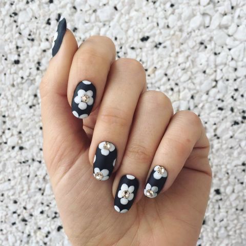 For a textured floral nail, this design mixes matte polish, regular polish and embellishments. Start with a matte base. Let dry, then paint flower petals in a glossy hue. Finish the nail with crystal accents glued to the center of each flower. Design by @jessicawashick