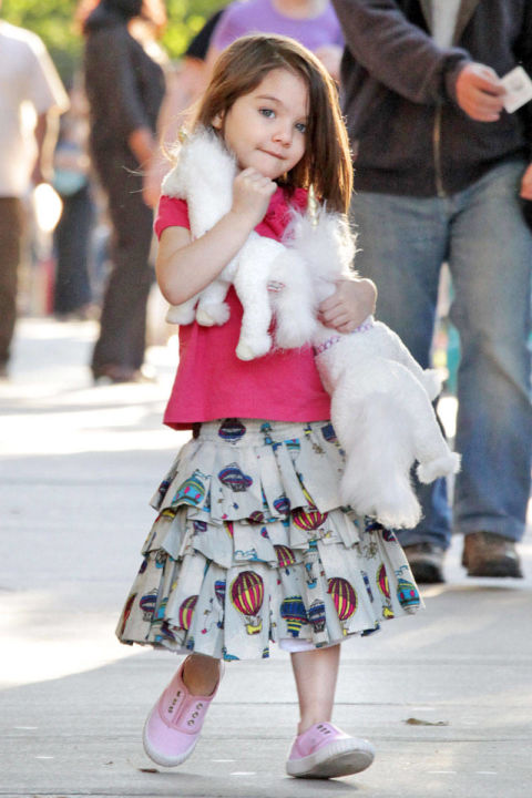She matches a pink T-shirt by Seed with a printed skirt and sneakers.